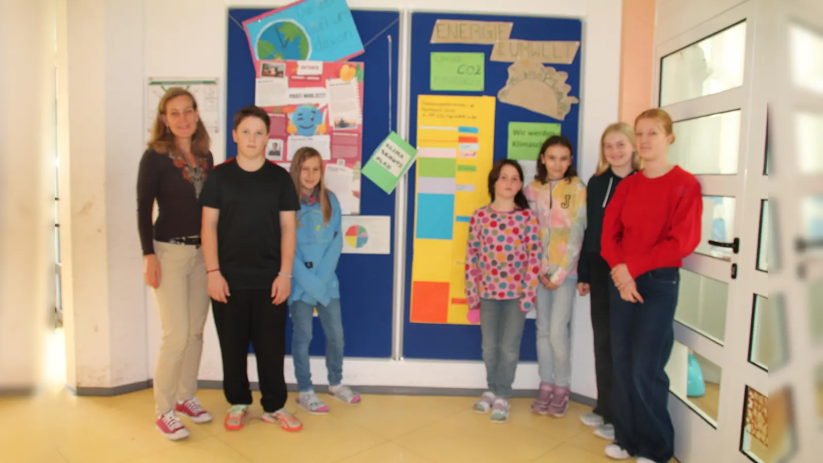 Im Eingangsbereich der Montessori-Schule wurden auf einer Klimawand verschiedene Maßnahmen und Fakten veranschaulicht: v.l. Heike Fliegerbauer, Felix, Josefine, Fine, Matilda, Aurelia und Mathilda. (Foto: bb)