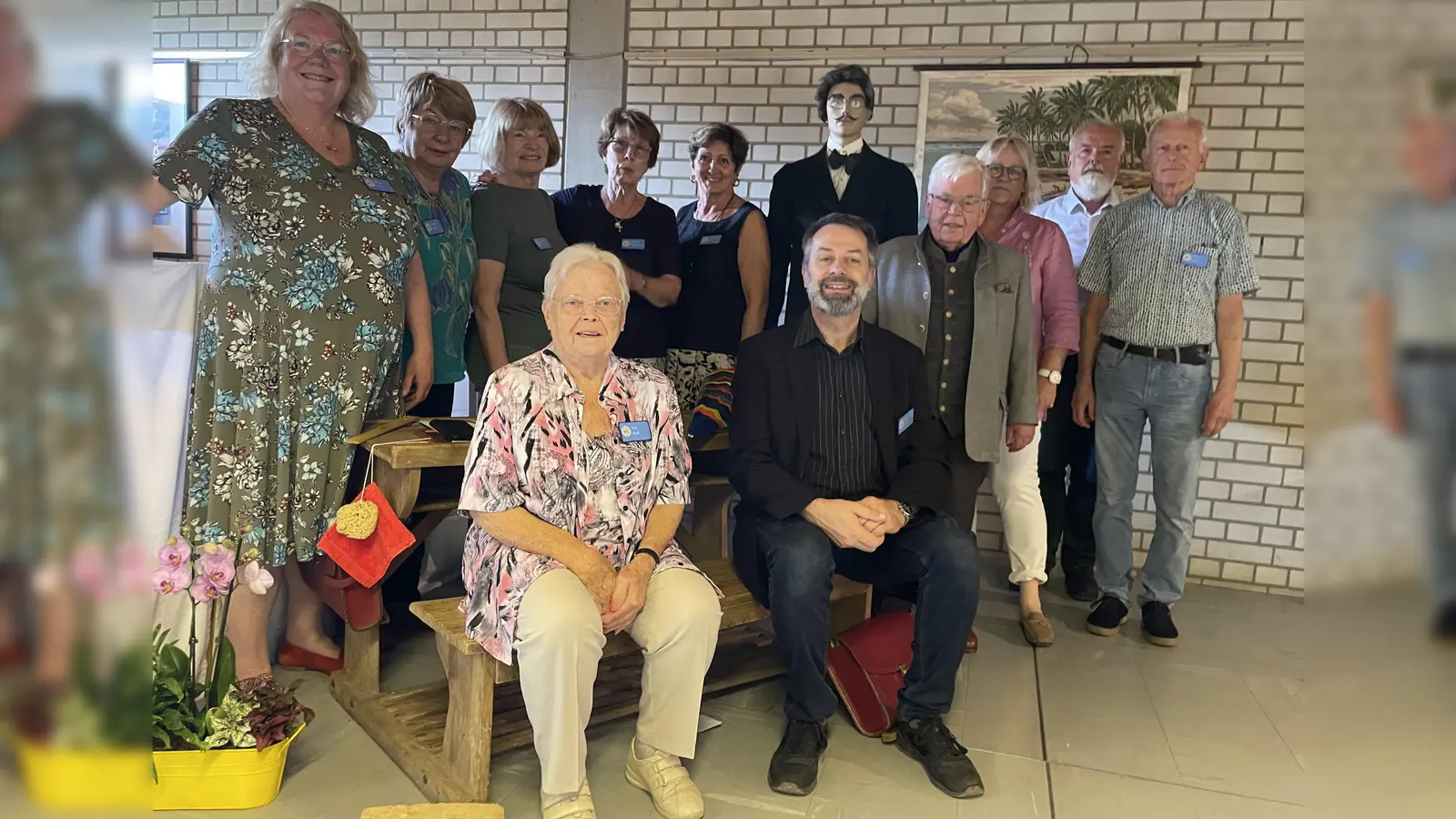 Die Teilnehmer des Vereins „Langwied Lochhausen Historisch” mit Vorsitzender Barbara Kuhn (links) und Stellvertreter Detlef Kohler (sitzend) mit einer Lehrer-Puppe (hintere Reihe) in dem nachgestellten Klassenzimmer. (Foto: pst)