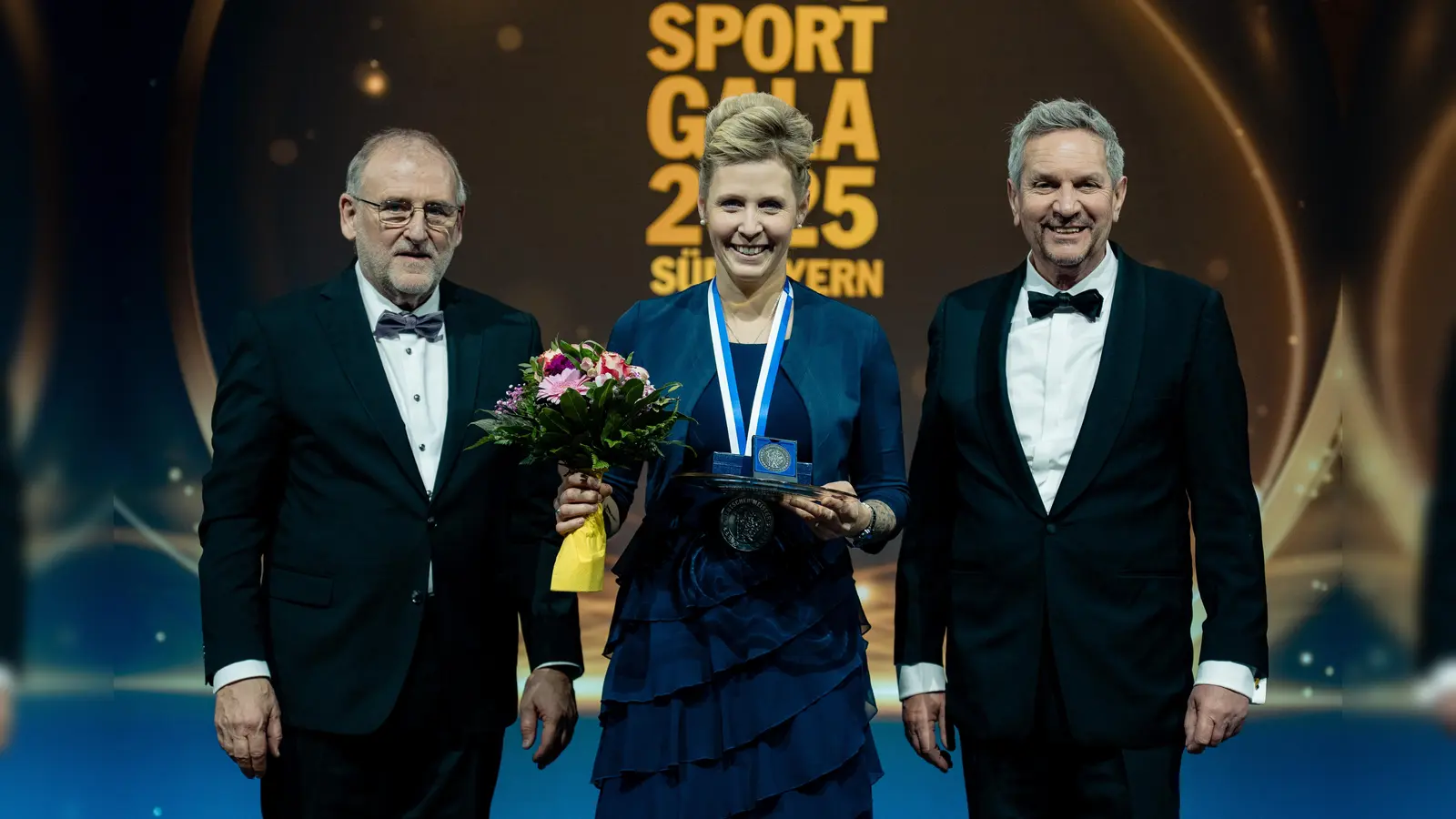 Simone Hain (Mitte) freut sich über die Ehrung, die von Gerd Ennser, Vorsitzender des ADAC Südbayern, sowie Fritz Schadeck, Vorstand für Jugend und Sport, überreicht wurde. (Foto: ADAC Südbayern/Flo Huber )