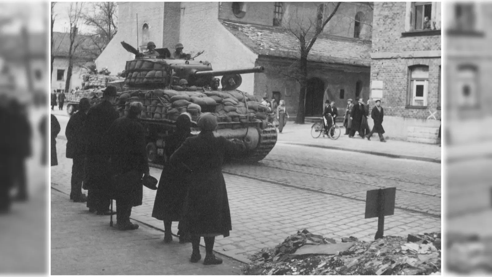 Am 30. April 1945 rücken amerikanischer Panzer in der Plinganserstraße vor (im Hintergrund St. Achaz). Münchner beobachten den Einmarsch am Straßenrand. (Foto: Stadtarchiv München (FS-PK-ERG-09-0261))
