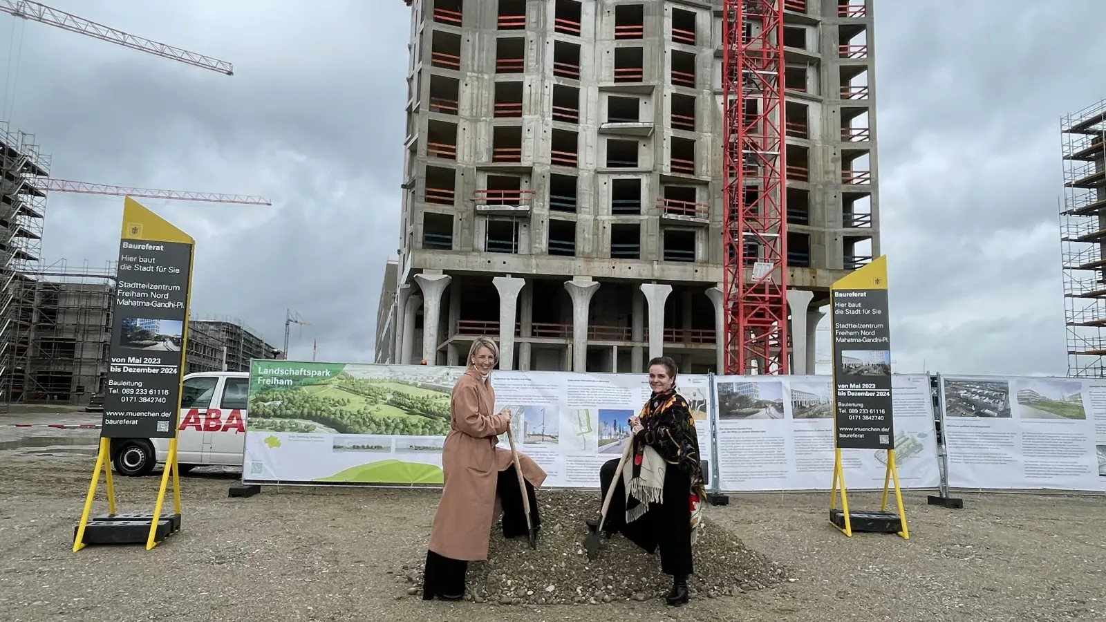 Bürgermeisterin Katrin Habenschaden (li.) und Baureferentin Jeanne-Marie Ehbauer führen den symbolischen ersten Spatenstich aus. Vor dem Rohbau des Hochhauses wirken sie winzig klein. (Foto: pst)