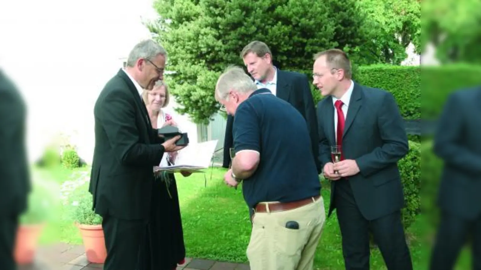 Polizei-Oberrat Klaus Hofmann (im Hintergrund, Mitte) bekam im Garten des Pfarrhofs von Herrn Stadtpfarrer Zott (li.) Dankens-Zeichen der Pfarrei Maria Schutz überreicht. (Foto: pi)