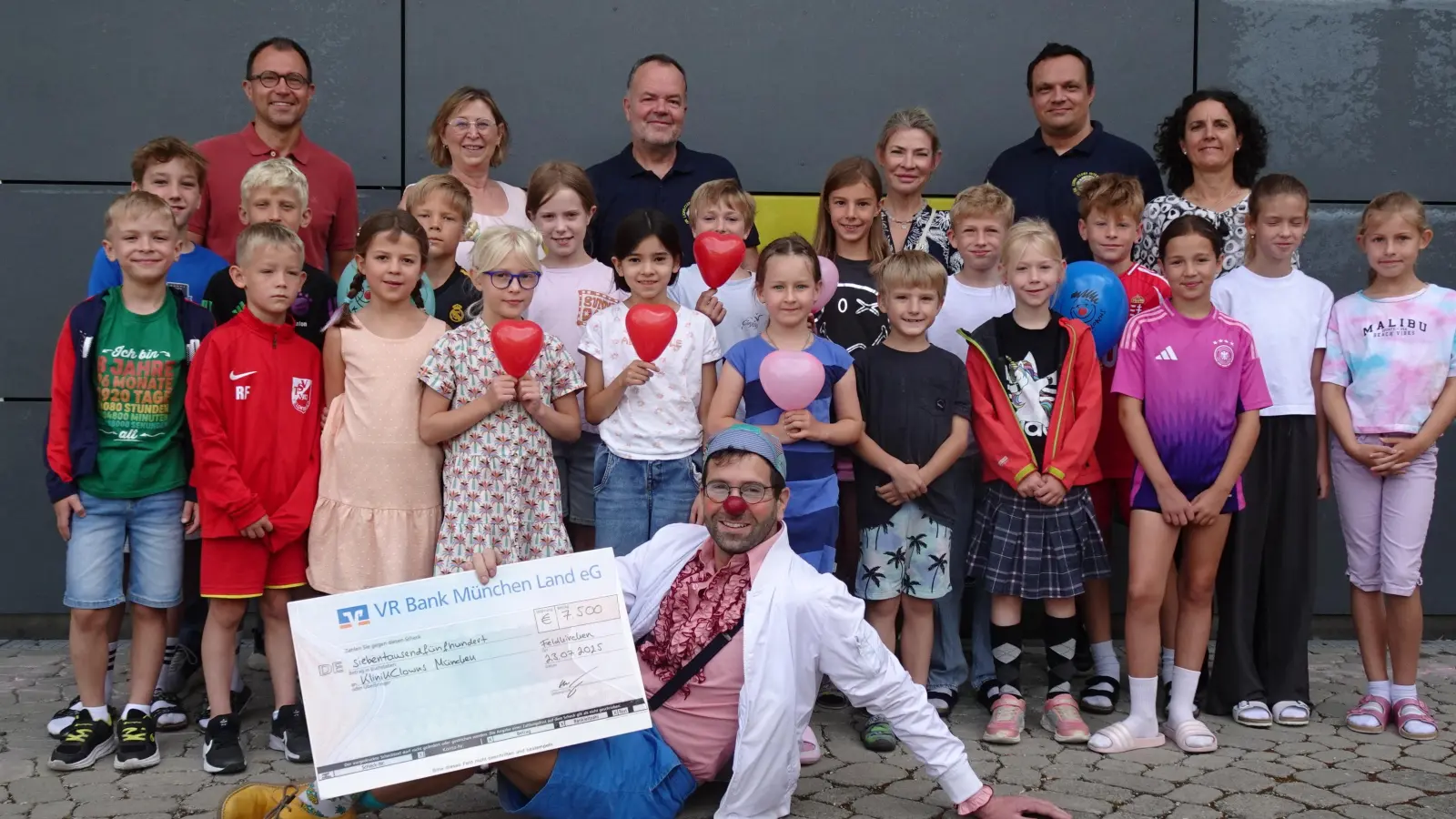 Hinten von links: Alexander Bolotnik vom Elternbeirat, Schulleiterin Sabine Schmidt, Lions-Präsident Wolfgang Frank, Alla Mühlenfeld vom Elternbeirat, René Beyer, Organisator des Spendenlaufs, und Sportlehrerin Cornelia Kellerer. Unten: Klinikclown Georg Schulze alias Dr. Batscho. In der Bildmitte: viele kleine Athleten der Grundschule Feldkirchen. (Foto: Lionsclub Aschheim Herzog Tassilo III.)